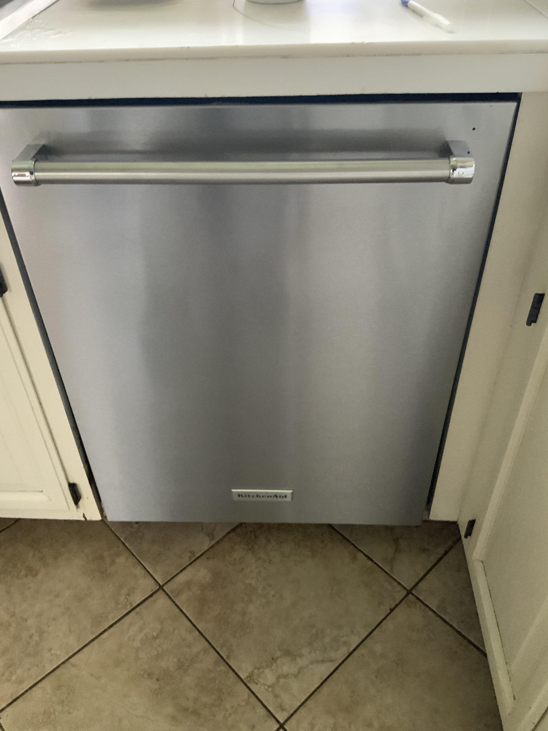 Technician fixing KitchenAid KDTE234GPS0 dishwasher with drain issues in Alliance, Ohio.