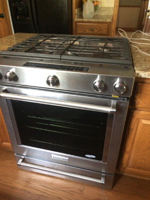 KitchenAid KSGB900ESS0 oven displaying functional burners and controls post-repair.